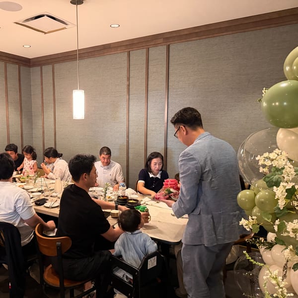 A family dines at a restaurant, with a server presenting a platter of raw meat.