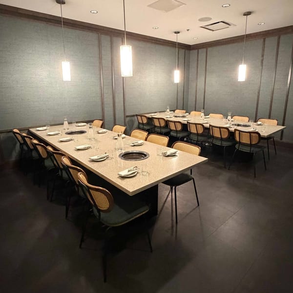 A private dining room with two long tables set with plates, glasses, and built-in grills.