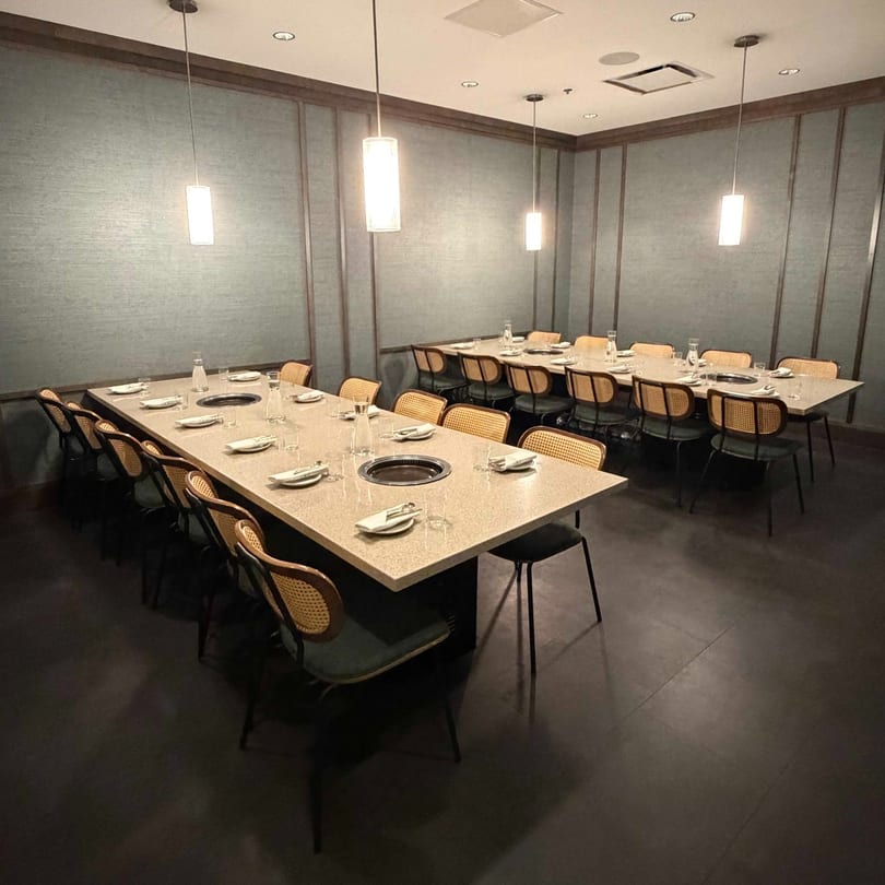 A private dining room with two long tables set with plates, glasses, and built-in grills.