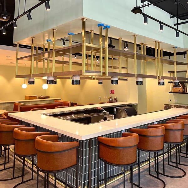 MOA Korean BBQ & Bar's modern bar area with brown leather stools and gold shelving.