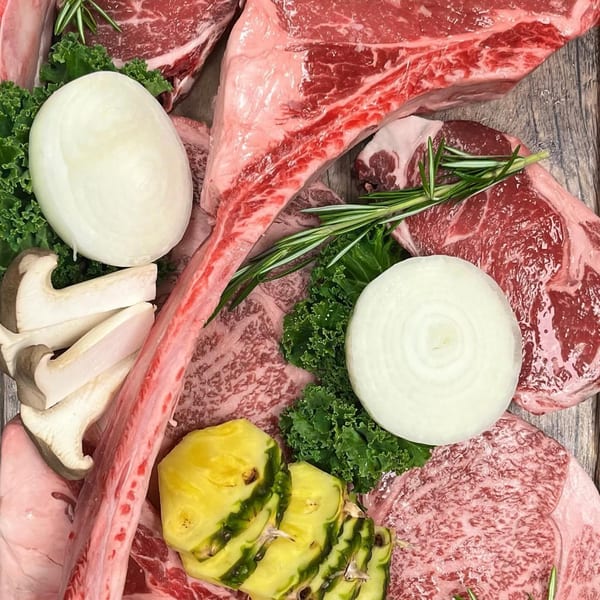 Assortment of raw Korean BBQ meats, onions, mushrooms, pineapple, and rosemary on a wooden surface.