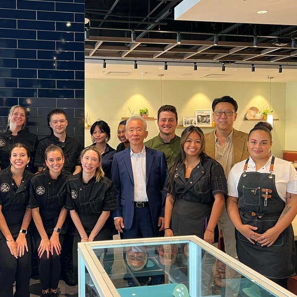 MOA Korean BBQ & Bar staff, including chefs in black uniforms and two men in suits, posing together.
