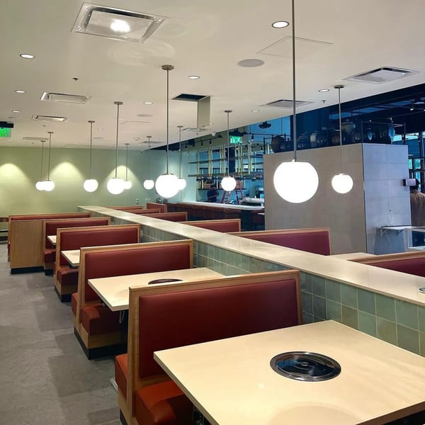 MOA Korean BBQ & Bar's dining area with red booths, light tables, and spherical pendant lights.