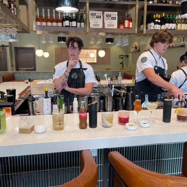 MOA Korean BBQ & Bar bartenders preparing cocktails at a well-stocked bar with various drinks.