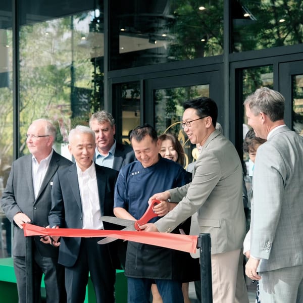 Group of people, including a chef, cutting a red ribbon for the MOA Korean BBQ & Bar opening.