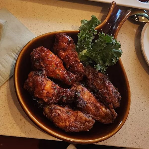A brown bowl of MOA Korean BBQ & Bar's crispy, glazed Korean fried chicken wings with kale.