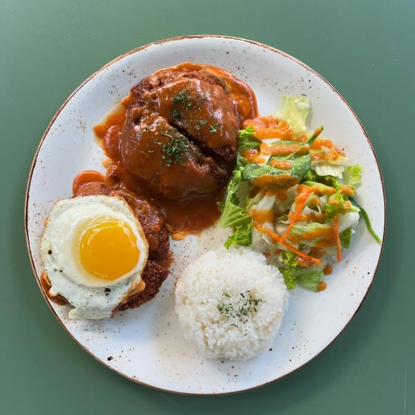 MOA Korean BBQ & Bar's Loco Moco with gravy-covered patties, fried egg, rice, and salad.