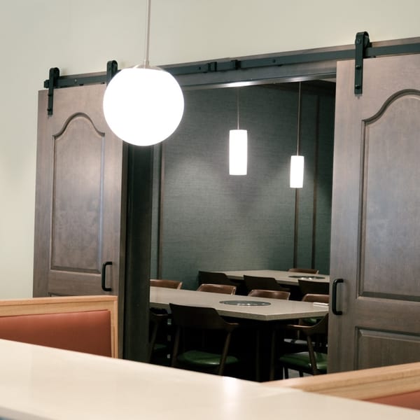 A restaurant dining room with a large wooden sliding door revealing tables and chairs inside.